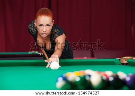 Sexy pool player. Beautiful young red hair woman playing pool