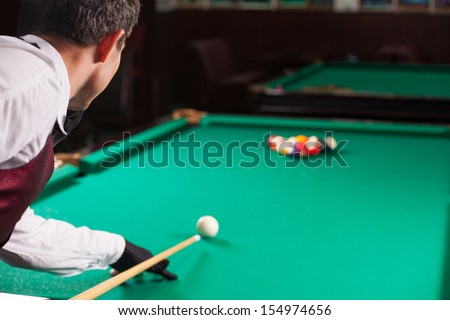 Playing pool. Rear view of man aiming the billiard ball with cue