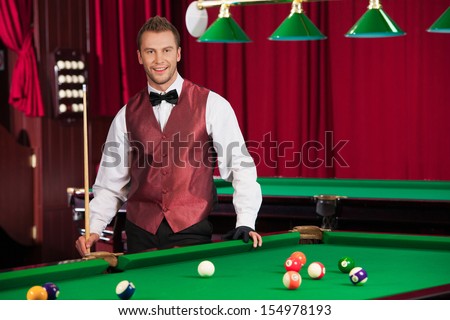 Pool player. Confident young pool player holding cue and smiling