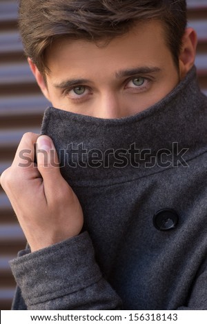 Man in coat. Handsome young man adjusting his coat and looking at camera