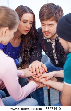 Group of people sitting in a circle. Holding hands together palm to palm