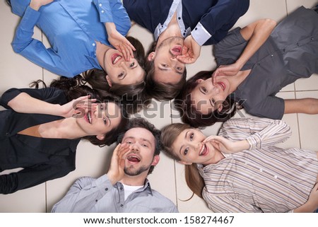 Top view of people laying in circle together. Everyone is telling something holding a  hand near mouth