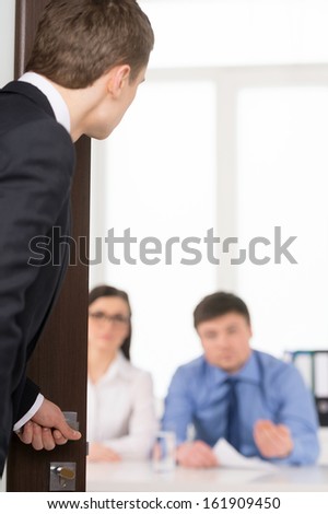 Worried man entering a room for job interview. Two Human Recourses Agent sitting in office. Blur background