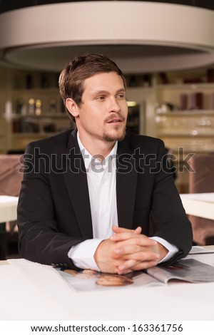 Single handsome business man sitting alone in luxury restaurant. Looking away