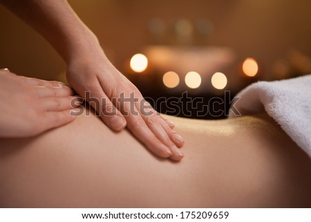 gentle hand massage of girl back. burning candles on background near sink