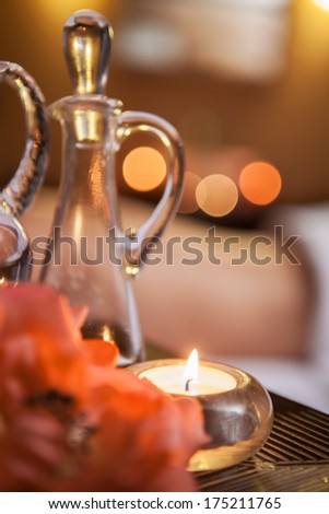 beautiful buring candle on table. beautiful glass jar of oil and flowers.