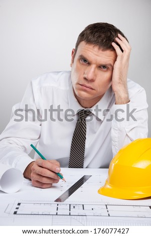 professional architect working with plan and thinking. man in white shirt sitting holding head