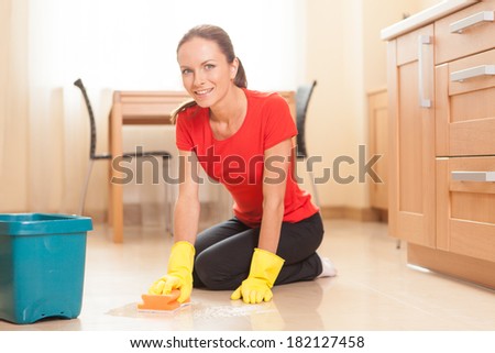young girl washing floor in kitchen. beautiful housewife doing cleaning and smiling
