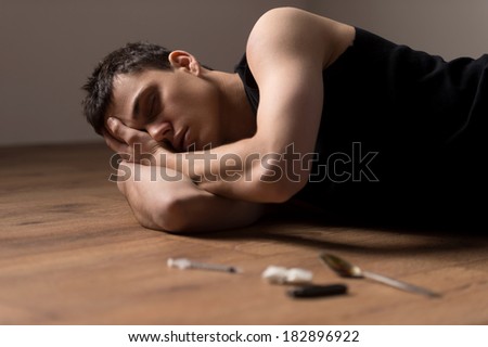 young handsome man lying on floor. wasted dude sleeping in bliss from drugs