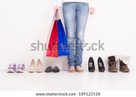 Trying on Shoes. Woman stands in a pair of open toe shoes with many other options on the floor