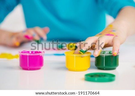 Adorable girl finger painting. Adorable girl finger painting - just dipping her finger into the paint