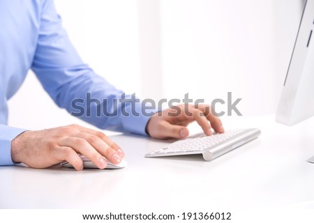 Businessman working with desktop computer. Focus on human hands and computer keyboards.