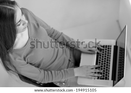 Young woman sitting on chair and checking email. black and white picture of girl working on computer