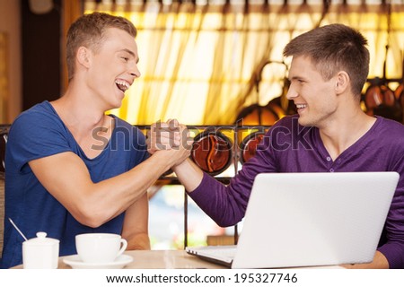 two friends shaking each other hands. handsome guy laughing and talking to friend