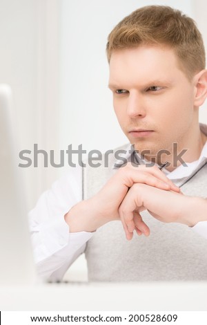 handsome young man looking at screen. front view of man sitting at laptop computer
