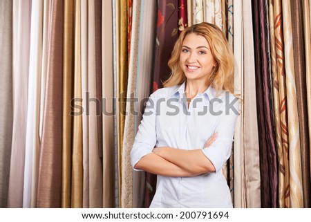 blond girl standing in fabric store. beautiful lady selling tissue and smiling