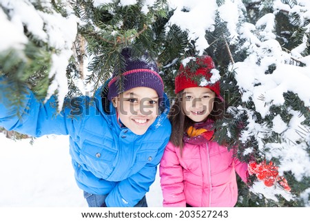 boy and girl hiding under pine tree. sister and brother playing in trees and smiling