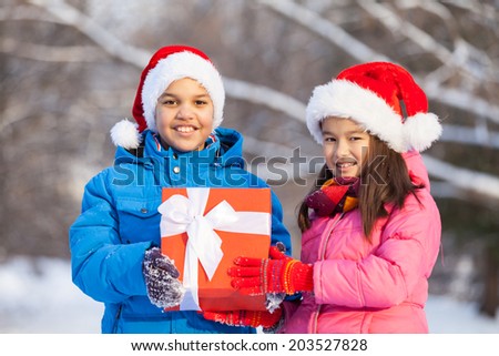 brother and sister holding present together. two children celebrating birthday outside