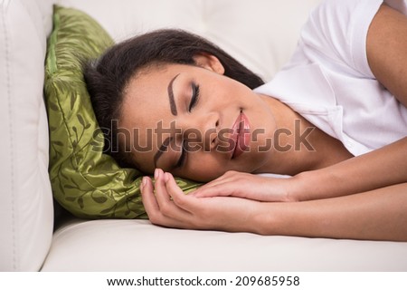 Radiant woman sleeping on sofa in living room. Young African American Female Taking Nap