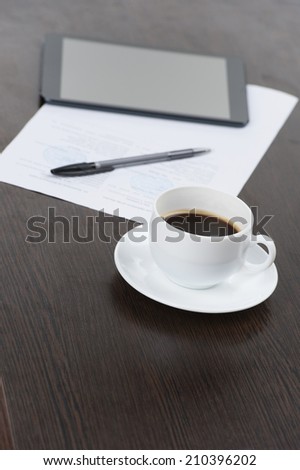 Tablet computer with cup of coffee and pen at table. closeup photo of coffee and computer on black table