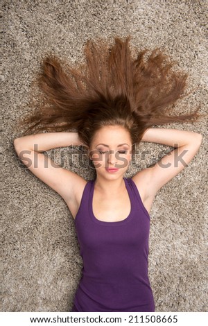 Relaxed woman lying on floor indoors and sleeping. Beautiful young woman lying on floor