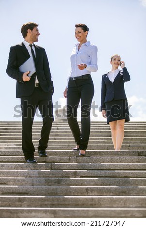 Three happy business people walking together outside. three business partners standing on stairs and talking