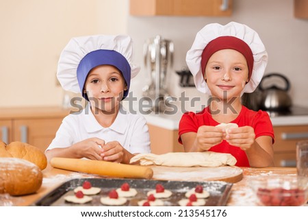 little children making cakes and smiling. two kids having fun at kitchen table