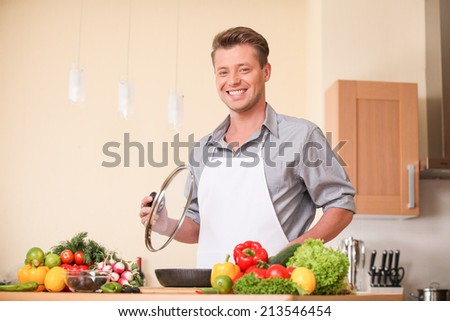 waist up of man holding frying pan lid. guy preparing healthy food at kitchen