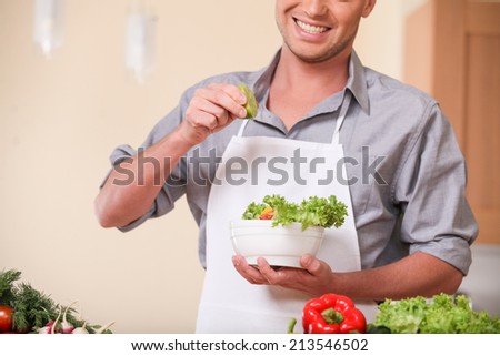 handsome man adding lime to fresh salad. guy preparing healthy food at kitchen
