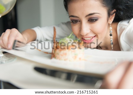 Closeup of woman's hands holding fork and knife. focused girl's face looking at food in restaurant