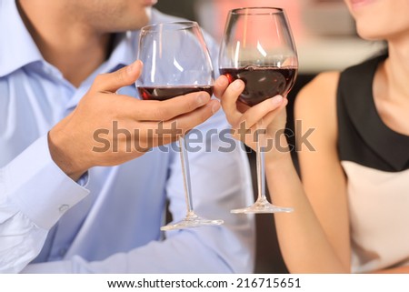 Two people toasting with wine glasses. cropped image of couple drinking red wine at restaurant
