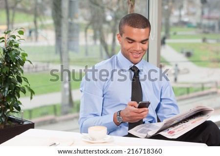 young handsome business man typing sms. cool guy reading newspaper and smiling