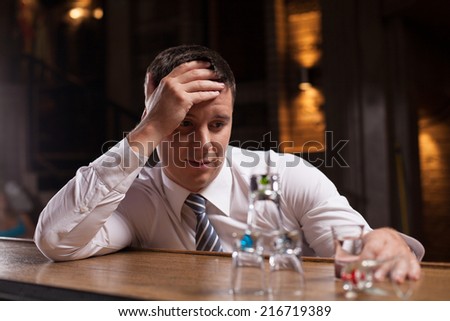 Upset businessman having drink in bar. closeup of man looking at glasses pyramid