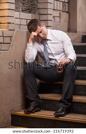 Handsome young man sitting on stairs. portrait of guy drinking whisky and sleeping