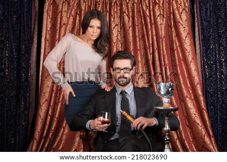 woman standing behind man in Arabic cafe. man and woman smoking hookah and looking