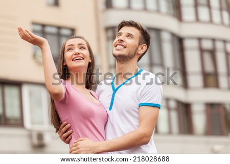 man huging woman under rain in city. woman and man standing outside and looking at rain