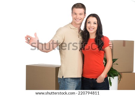 couple celebrating new home with keys and moving boxes. Happy couple moving into new apartment.