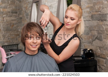 Blond female hairdresser cutting hair of man client. closeup on happy man sitting in hair salon and smiling