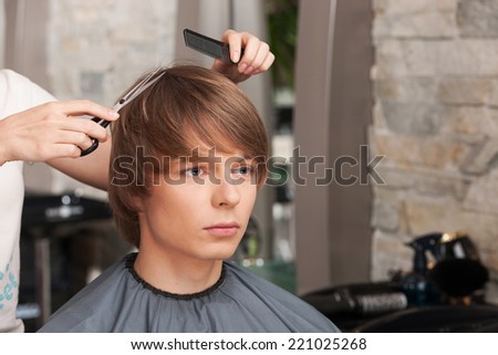 Female hairdresser cutting hair of man client. handsome man sitting in hair salon