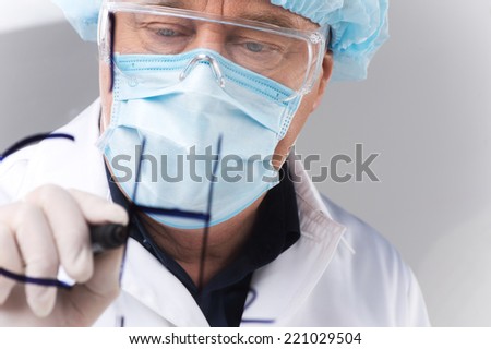 close-up of researcher writing formulas on transparent board. closeup on man wearing mask standing on white background