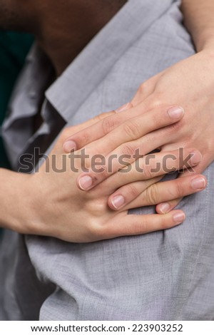 closeup of girl hands hugging boyfriend shoulder. side view of black man wearing shirt
