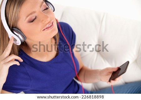 beautiful young girl listens to music on headphones. top view of happy woman with headphones resting on sofa