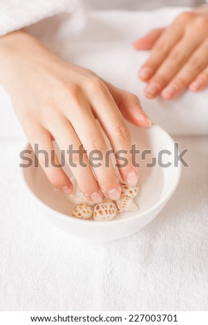Woman hands in glass bowl with water on white towel. closeup of female beautiful hands on white towels