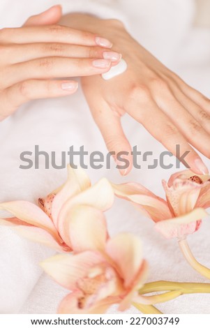closeup of woman hands with white cream. image of beautiful female hands and fingers with flowers and towel