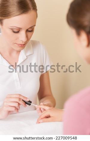 Close-up of beautician hand painting nails of woman in salon. manucurist women sitting in spa salon and looking at hands