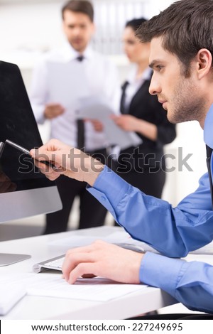 Handsome young man participating at training course. couple standing on background with man pointing to screen on foreground