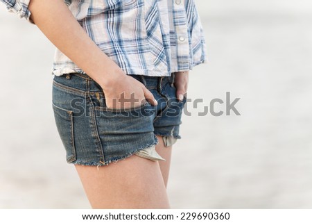 woman in jeans shorts walking on sand. closeup on girl holding hands in pockets of jeans shorts