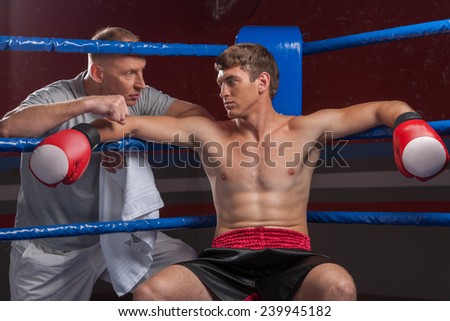 Senior coach advising boxer after end of round. two man in boxing ring talking