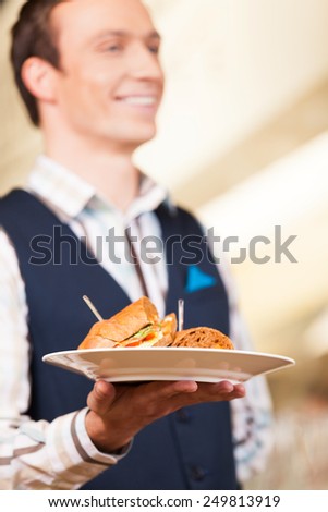 Waiter carrying one plate with sandwich. closeup on plate with sandwich in hands of waiter