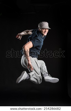 young dancer isolated on black background in studio. Young man dancing in dark studio with hat
